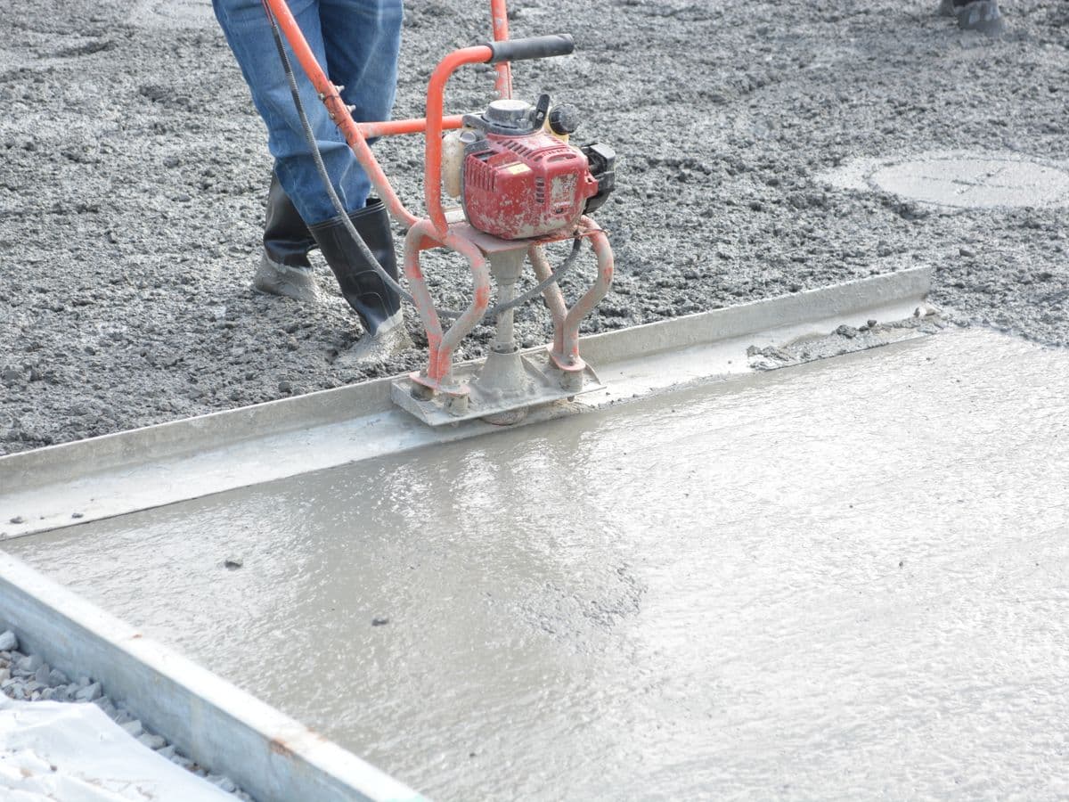 Close-up of a worker finishing a fresh concrete slab with a power trowel.