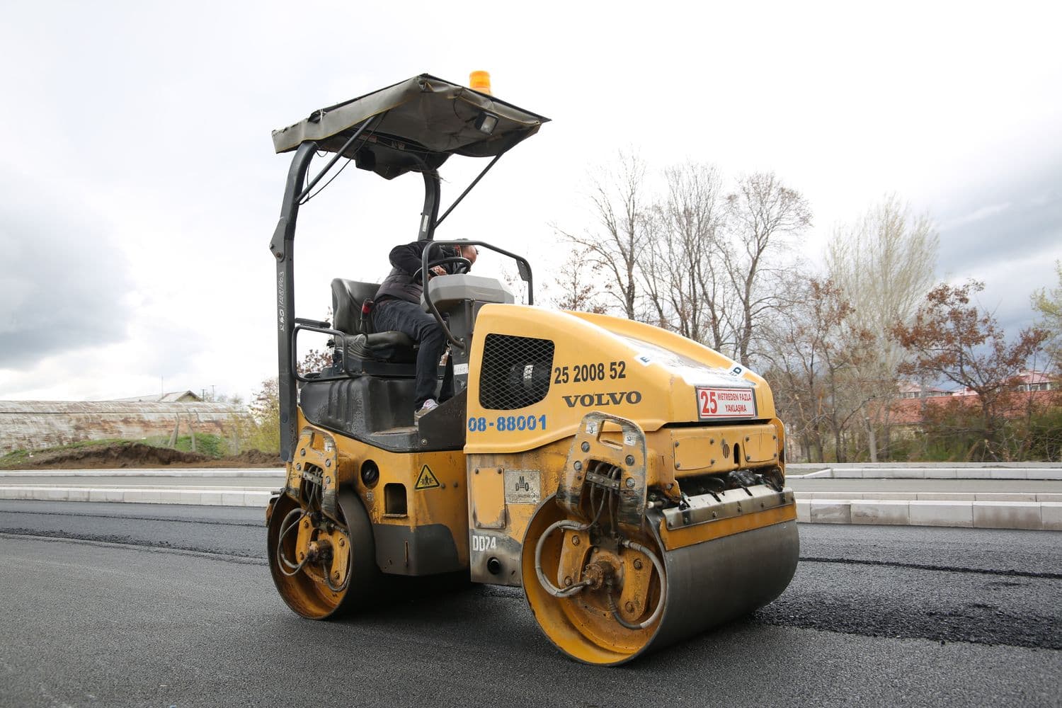 A vibratory roller compacting a fresh concrete and pavement surface on a job site.